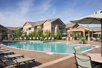 A swimming pool with chairs and umbrellas in front of a house
